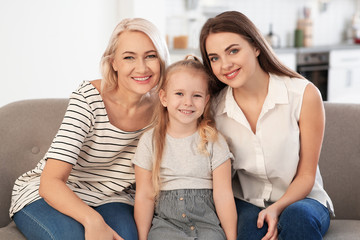 Canvas Print - Portrait of young woman, her mature mother and daughter on sofa in living room