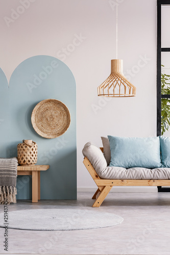 Dekoracja na wymiar  wiklinowy-zyrandol-nad-drewniana-skandynawska-sofa-z-futonem-w-jasnym-wnetrzu-salonu