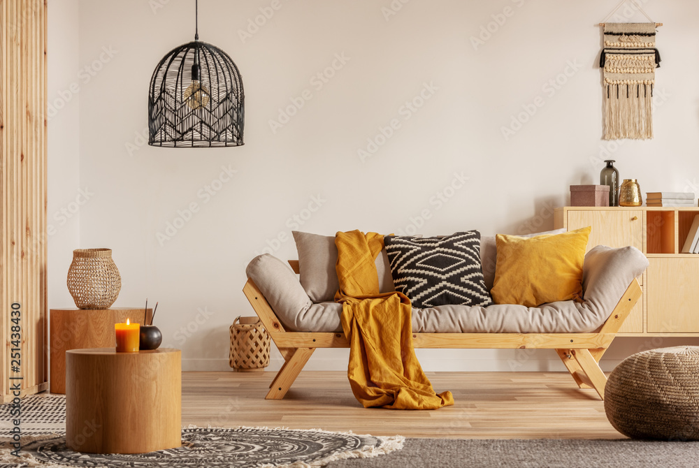 Scandinavian sofa with pillows and dark yellow blanket in bright living room interior with black chandelier - obrazy, fototapety, plakaty 