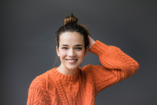 Portrait Of Happy Woman Wearing Orange Knit Pullover Against Grey Background
