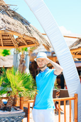 guy in sunglasses and summer hat staring at camera with hand ove