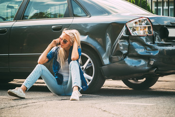 girl sits on the road, near the broken car and calls on the phone, calling for help.