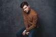© opolja - handsome casual man sits on chair near a dark gray wall and looks to side, portrait picture.