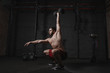© Arsenii - Crossfit athlete exercising at the gym doing overhead dumbbell squats.