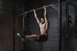 Crossfit athlete doing abs exercise on horizontal bar at the gym. Handsome man doing functional training workout. Practicing calisthenics.