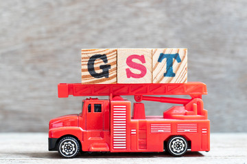 Canvas Print - Red fire truck hold letter block in word GST (Abbreviation of Goods and Services Tax) on wood background