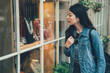 © PR Image Factory - Astonished woman looking showcase shop window. Surprised shopping girl chooses jewelry outside the store for mom birthday gift while travel in carmel by the sea town. female backpacker curious see