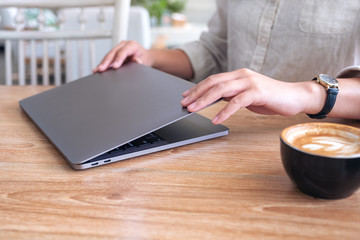 closeup image of a woman close and open a laptop computer on table after finished using it