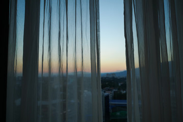 Wall Mural - sunlight through white curtain with sunset sky view outside the window