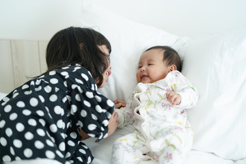 Wall Mural - Asian elder sister having fun with her newborn baby sister with love. family concept.   