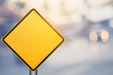 Empty Yellow Traffic Sign On Blur Traffic Road With Colorful Bokeh Light Abstract Background.