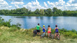 © Iuliia Sokolovska - Family on bikes cycling outdoors, active parents and kids on bicycles, aerial view of happy family with children relaxing near beautiful river from above, sport and fitness concept