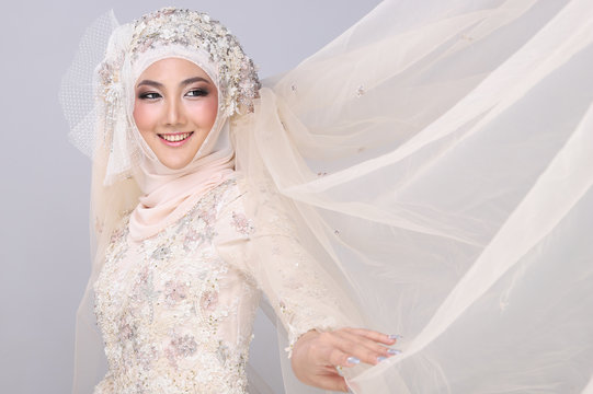 Asian Charming muslim arabic bride in Lace Bead Embroidery creammy yellow wedding dress and hijab headscarf, close-up on Fashion Make up Eyes Face, studio lighting grey background isolated.