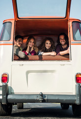 Wall Mural - A group of young friends on a roadtrip through countryside, looking out of window.