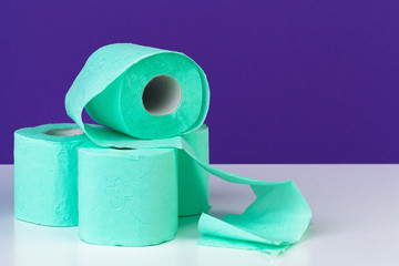 Toiletries. Rolls of green toilet paper on purple background