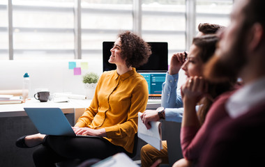 group of young businesspeople in office, listening to a presentation.