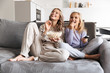© Drobot Dean - Happy young woman with her little sister indoors at home watch tv.