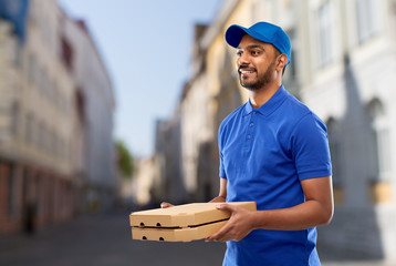 Wall Mural - takeaway service and people concept - happy indian delivery man with pizza boxes in blue uniform over old tallinn city street background