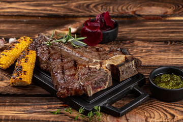 Wall Mural - Medium rare grilled Steak Ribeye Black Angus with corn and rosemary on serving on wooden background