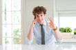 © Krakenimages.com - Young business man talking on smartphone at the office doing ok sign with fingers, excellent symbol