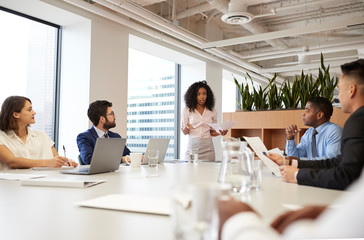 Businesswoman Standing Giving Presentation To Colleagues In Modern Open Plan Office