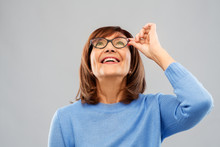 Vision And Old People Concept - Portrait Of Smiling Senior Woman In Glasses Looking Up Over Grey Background