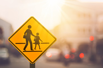 Wall Mural - School zone warning sign on blur traffic road with colorful bokeh light abstract background.