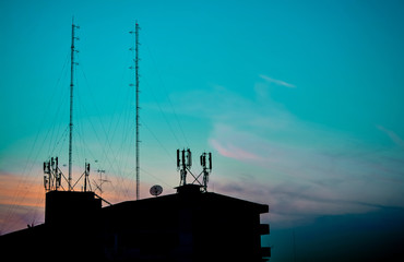 Silhouette of buildings at sunset view house and communication radio tower on blue sky