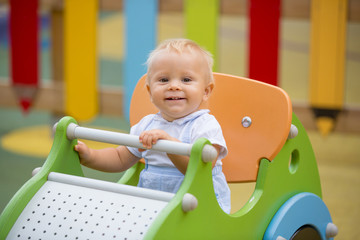 Wall Mural - Adorable baby boy, playing with different rides on the playgdorund