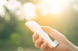 © tonktiti - Woman hand using smart phone at outdoor nature park with sunset sky abstract background.