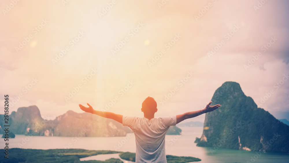 Feel good freedom and travel adventure concept. Copy space of happy man raise hands on  top of mountain with sun light abstract background. - obrazy, fototapety, plakaty 
