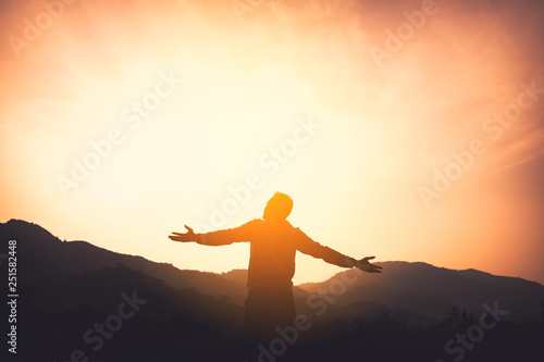 Fotomural Copy space of man rise hand up on top of mountain and sunset sky abstract background
