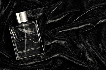 Male perfume bottle with copy space on black fabric background