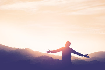 copy space of man rise hand up on top of mountain and sunset sky abstract background.