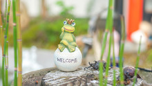 Garden/Home Decoration Of A Green Frog Sitting On A White Stone With The Word 'Welcome' Carved On It.