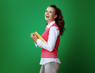 Wall Mural - happy young student woman holding yellow book and looking up