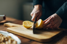 Chef cutting lemons on a wooden board