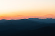© marina_larina - Panorama of the peaks of beautiful mountains covered with trees at sunset on a sunny day in summer. Orange glow on the sky after full sunset. Dark silhouettes of mountains. Solar reflection