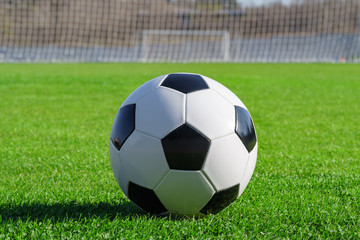 Classic soccer ball lies on the bright green grass on the football field in the designated area of the penalty area against the gate the sports stadium close-up in sports center for football players