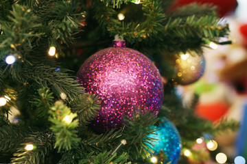 Wall Mural - Christmas card. Christmas picture. Bright sparkling orange ball on fluffy branches of a Christmas tree. Background bokeh lights of garland. Ready Christmas background for your text. Glitter.