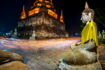 Wall Mural - Buddhists people walking with lighted candles in hand around a ancient temple