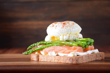 Poached egg with fried asparagus, cream cheese, salmon and spices on a toast. Poached egg with leak.Healthy French breakfast concept