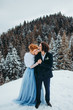© Yuliia - A crazy couple go to the winter pine forest, a woman in a blue wedding dress, a man in a suit