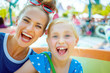 canvas print picture - smiling mother and child tourists in theme park having ride
