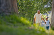 © Erickson Stock - Happy senior man walking hand in hand with his young granddaughter through a park.