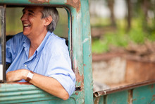 Mature Man Happily Sitting In Driver's Seat Of Truck.