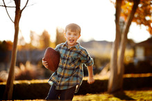 Portrait Of Running Boy Holding His Rugby Ball In The Backyard.