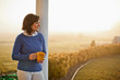 © Erickson Stock - Content mature woman standing on a front porch at sunset.