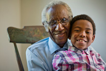 Portrait Of Smiling Grandfather Sitting On Rocking Chair With His Grandson