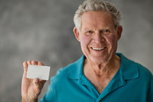 Portrait Of A Smiling Elderly Man Holding A Blank Card.